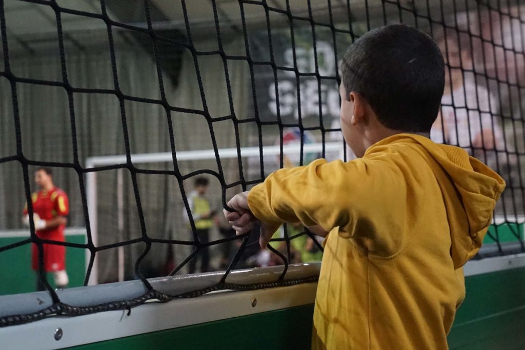 Kick it against hate! Kleiner Junge sieht beim Fußball spielen zu.