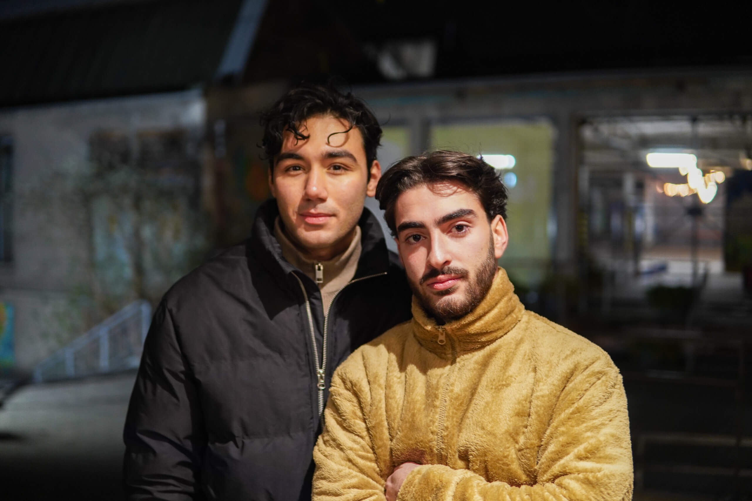 2 junge Männer vor dunklen Hintergrund schauen in die Kamera